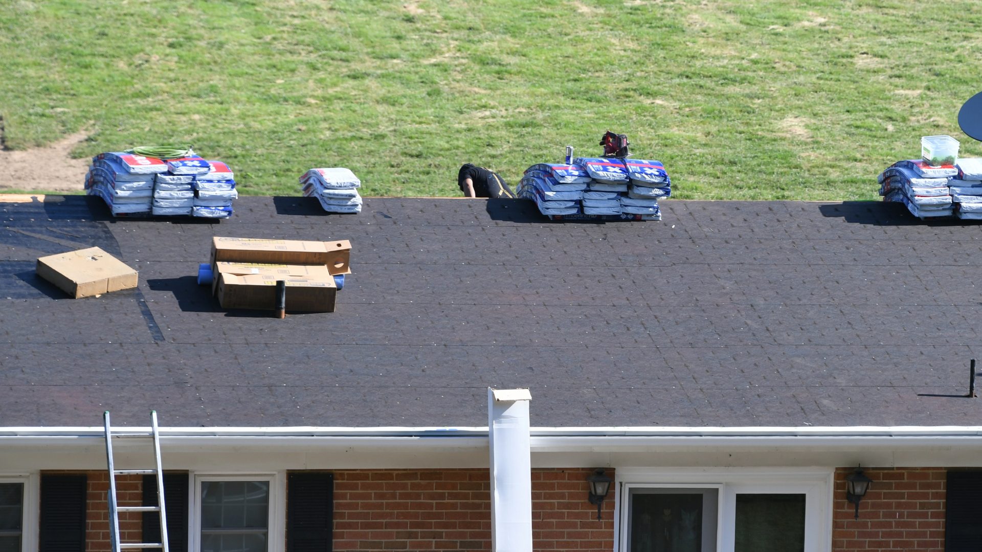 Roof repair NORR Roofers installing a new asphalt shingle roof on a red brick house.