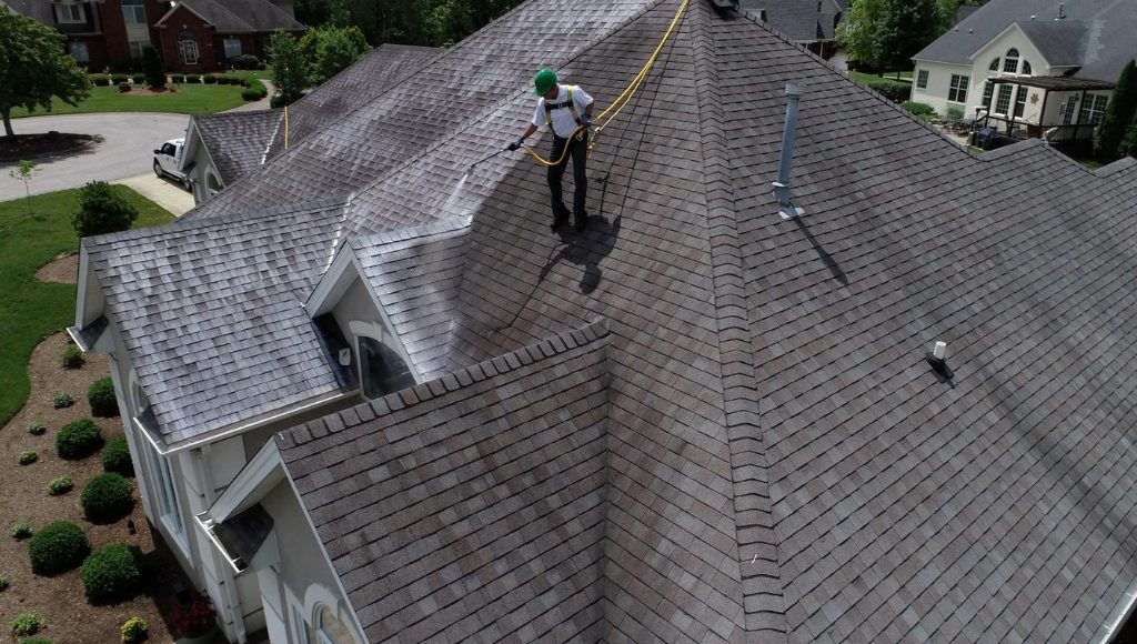 A Northern Ohio Roof Restoration worker sprays a roof down with Roof Maxx treatment.